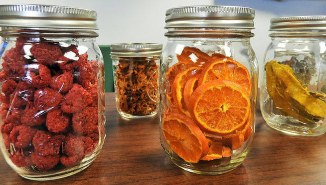 Assorted dried fruits including raspberries, orange slices, and bananas in mason jars, perfect for healthy snacking.