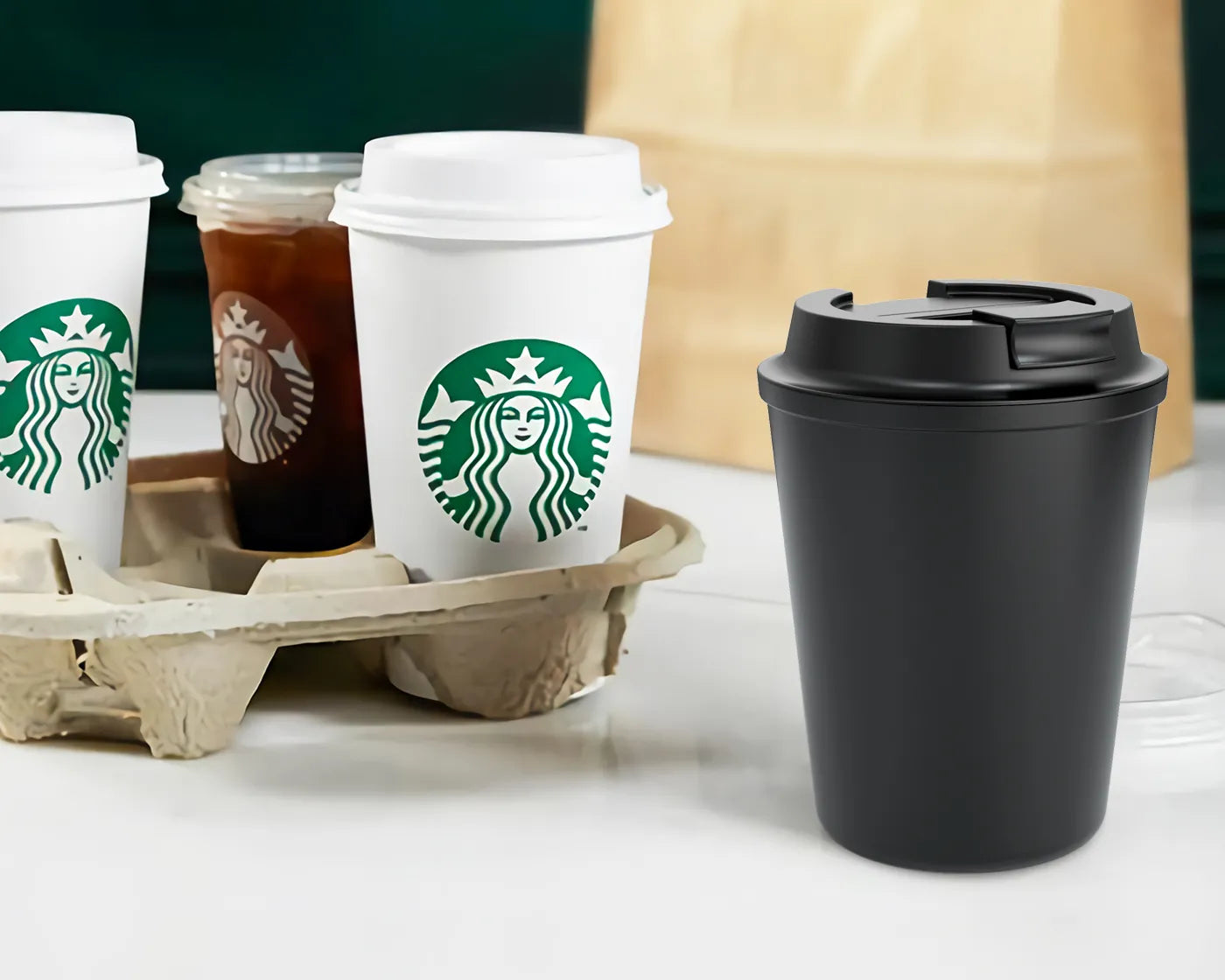 Black reusable coffee cup next to traditional disposable Starbucks cups for sustainable lifestyle.