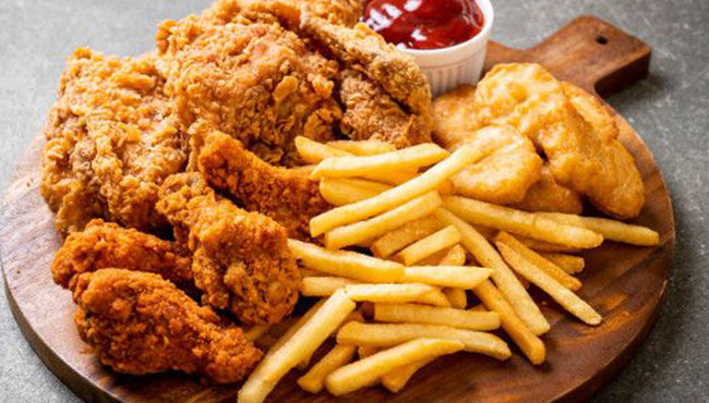 Crispy fried chicken with golden french fries on a wooden platter, a classic comfort food favorite.