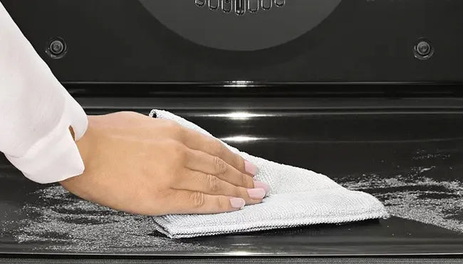 Close-up of a hand wiping clean the durable and easy-to-clean surface of a Ruokala oven after baking.