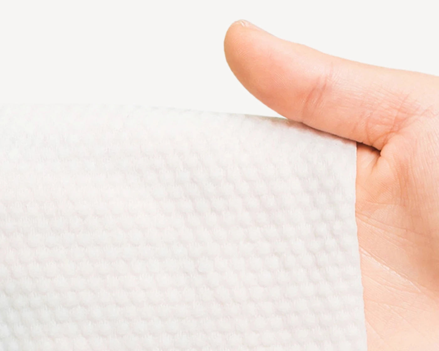 Person holding a textured white kitchen paper towel, demonstrating its thickness and quality.